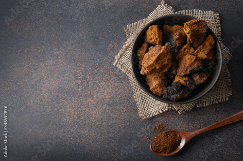 Chaga birch Mushrooms in bowl on black table. Trendy healthy superfood for infusion, tea or coffee. View from above. Copy space.