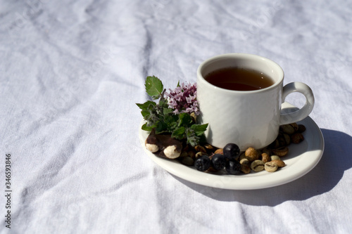 Coffee composition with white cup of coffe with herb and beans of coffe, Chocolate, berry, mint on linen tableclothtable