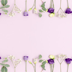 Frame made of eustoma, gypsophila flowers and eucalyptus with copy space. Floral concept on a purple pastel background.