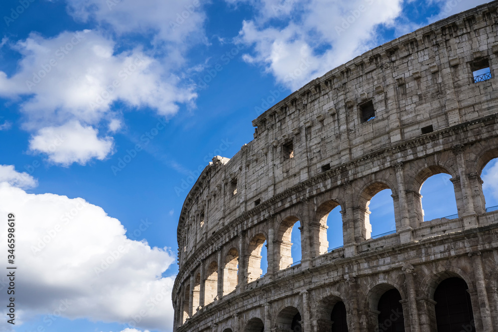 Close view of the Colosseum with blue sky and clouds. Also known as the Flavian Amphitheatre, it is one of the most popular attractions of Rome in Italy.