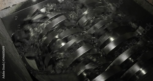 Working shredder mashine shreddering rubber car tires on processing plant, closeup view. Environmental protection, recycling of used materials. Recycled automobile tyres on factory.