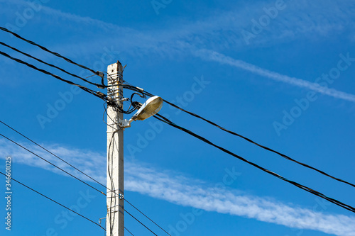 Wallpaper Mural A concrete electric pole with a street lamp and lots of wires against a blue sky Torontodigital.ca