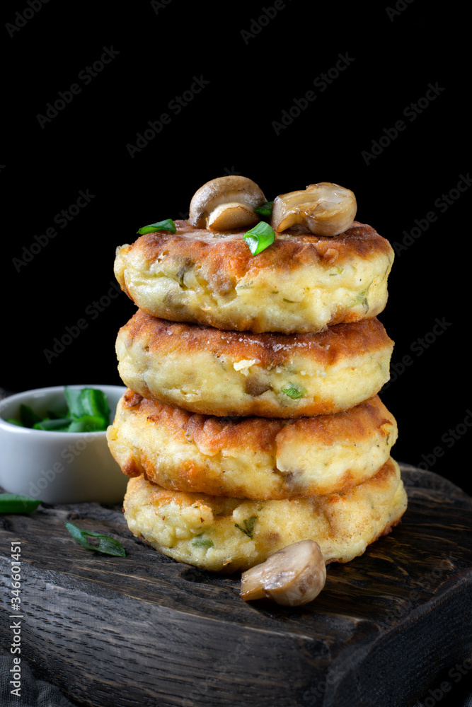 Stack of salty syrniki with champignons and herbs against the black background