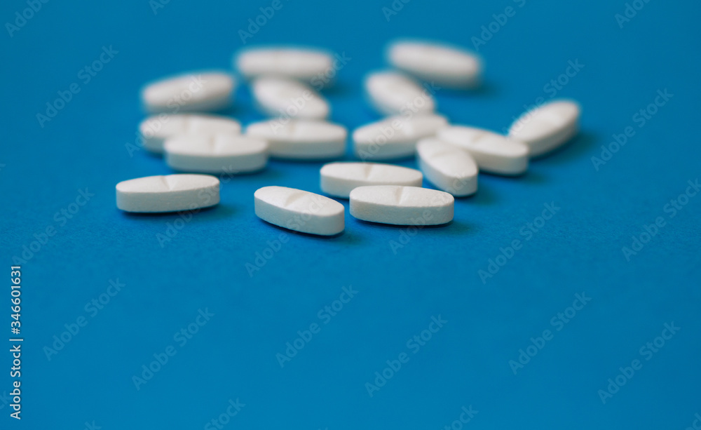 White tablets on a blue background close-up. Macro pills. Medical care for flu and colds. Protection from Covid19 White tablets on a blue background close-up. Macro pills. Medical care for flu and colds. Protection from Covid19