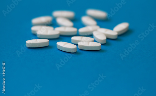 White tablets on a blue background close-up. Macro pills. Medical care for flu and colds. Protection from Covid19