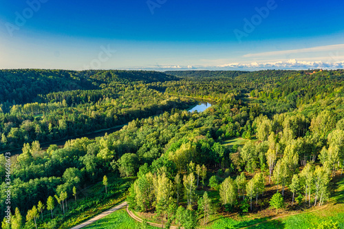 Aerial sight of warm, colorful autumn morning sunrise mist endless forest covered picturesque river valley with road