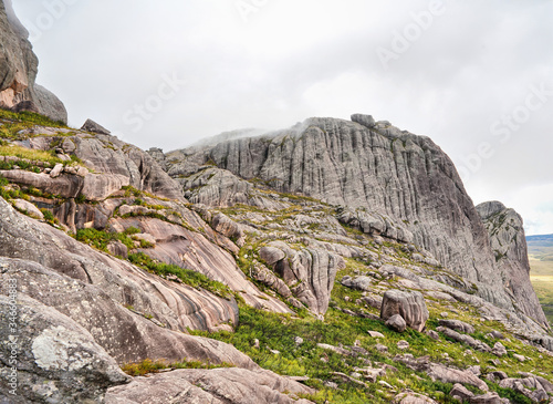 Tall rocky massif with low grass and bushes growing over stones - typical scenery seen in Andringitra during trek to Pic Boby peak photo