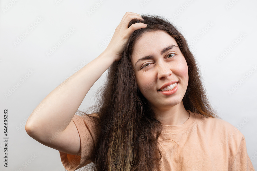 Dandruff and lice. Portrait of a young Caucasian brunette woman in a beige t-shirt, who strongly scratches her head with her hand. Copy space. White background Dandruff and lice. Portrait of a young Caucasian brunette woman in a beige t-shirt, who strongly scratches her head with her hand. Copy space. White background