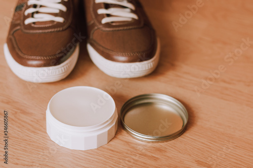 Taking care of shoes. Package of wax in front of casual, modern men's shos in blurred background. photo
