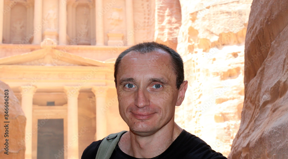 Obraz premium Smiling europian tourist man in sunglasses and black wear in Petra in Jordan during a journey.