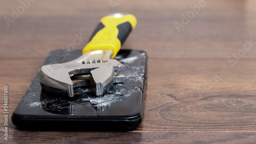 The wrench lies on a broken phone, phone repair, copy space
