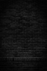 Black brick walls that are not plastered background and texture. The texture of the brick is black. Background vertical of empty brick basement wall.