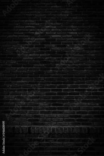 Black brick walls that are not plastered background and texture. The texture of the brick is black. Background vertical of empty brick basement wall.