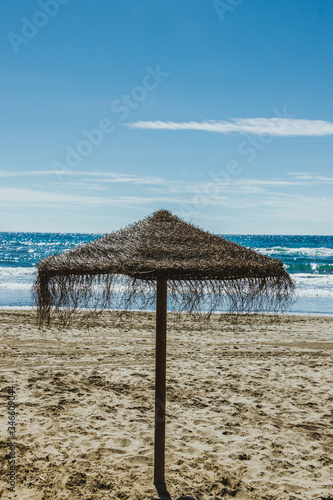 Straw umbrellas on empty beach in Marbella, Spain.