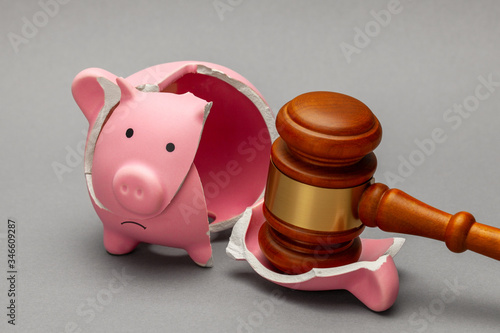 Broken piggy bank and judge gavel. on gray background. Bankruptcy, crisis concept