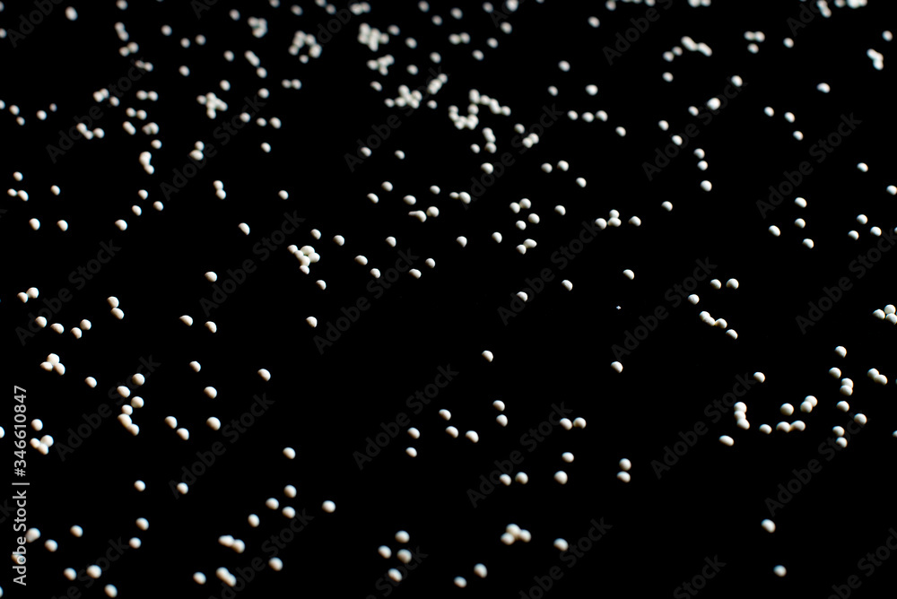 white confectionery sprinkle in the form of balls on a black background white confectionery sprinkle in the form of balls on a black background