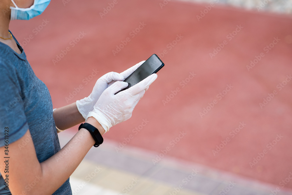 Woman using phone with protective gloves and mask