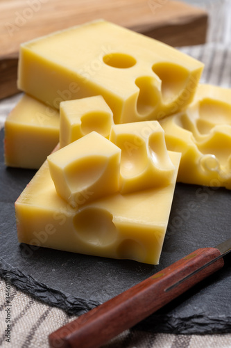 Block of Swiss medium-hard yellow cheese emmental or emmentaler with round holes and cheese knife photo