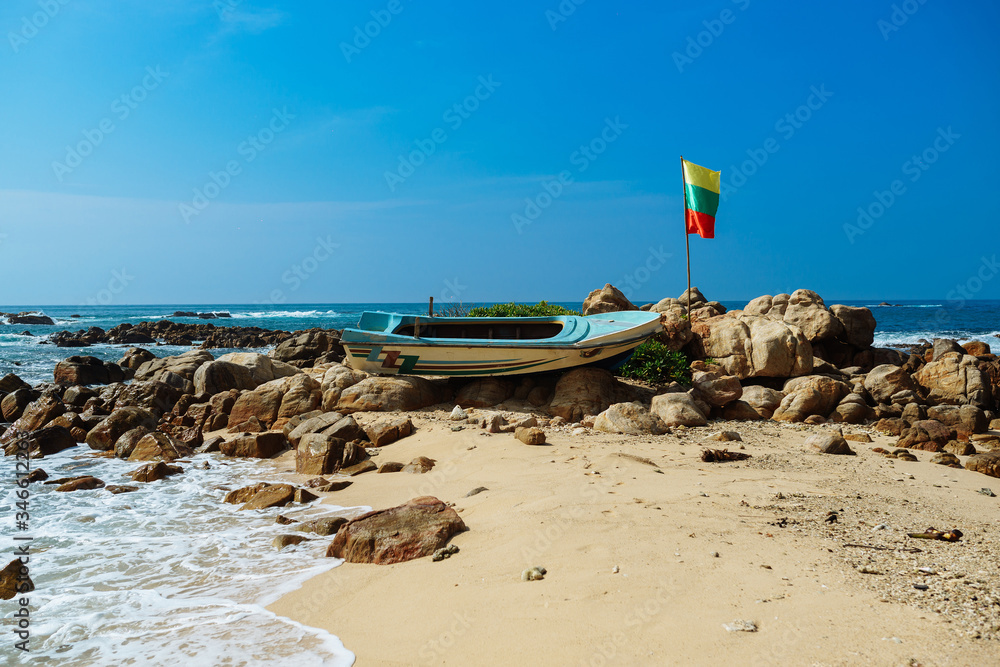Old boat with flag on secret beach, Sri lanka Old boat with flag on secret beach, Sri lanka