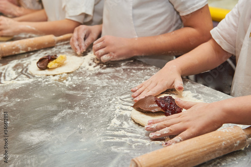young children fill a flour product with a sweet filling. Master class baking