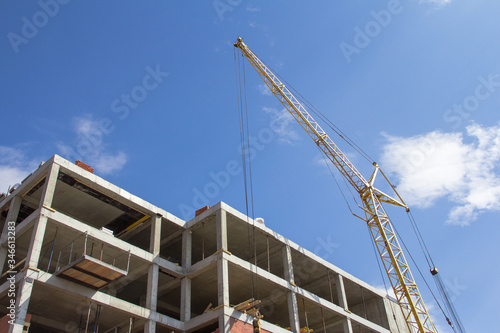 Construction technologies. Construction of a building made of reinforced concrete and a construction crane against the blue sky photo