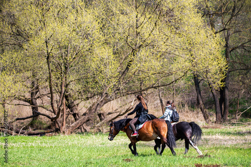 riders and horses on vacation in the forest by the river