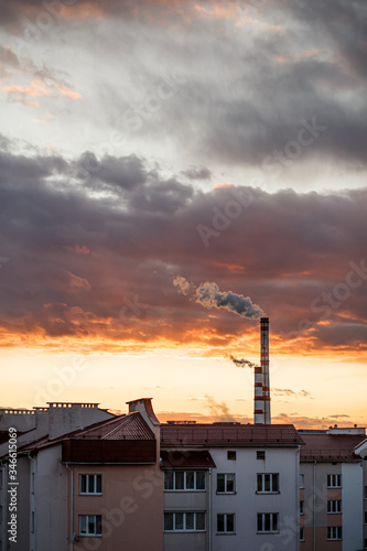 Steam or smoke comes from the pipes. Combined heat and power plant in the city. Landscape at sunset or dawn