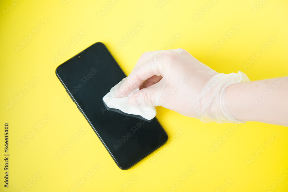 Hand In Protective Glove With Napkin Cleaning Mobile Phone. Coronavirus Disinfection Concept. Hand In Protective Glove With Napkin Cleaning Mobile Phone. Coronavirus Disinfection Concept.