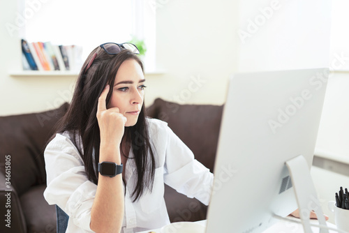 Portrait of attractive dark haired woman drinking coffee while working from home , freelance business woman