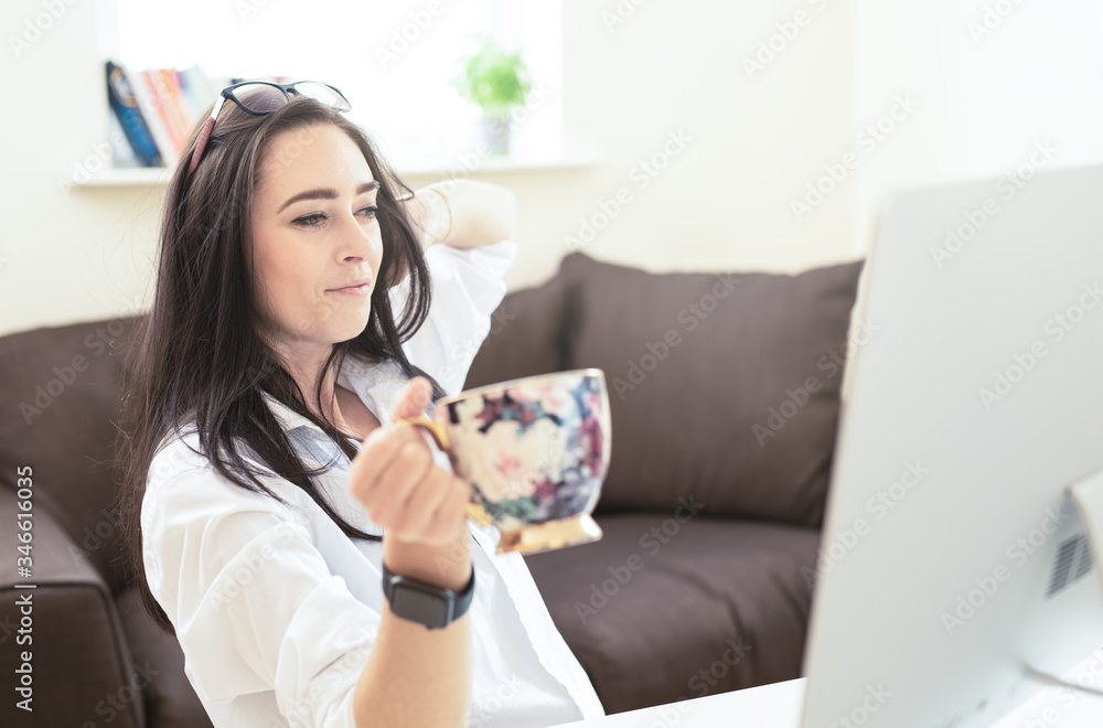 Portrait of attractive dark haired woman drinking coffee while working from home, reading emails on laptop , freelance beautiful businesswoman making money from home Portrait of attractive dark haired woman drinking coffee while working from home, reading emails on laptop , freelance beautiful businesswoman making money from home