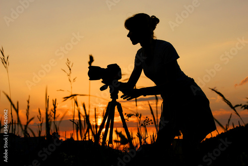 Fototapeta Naklejka Na Ścianę i Meble -  Silhouette of girl photographer against the background of sunset
