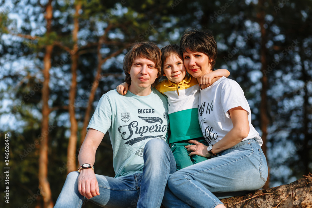 Father mother and son sit against the background of the forest