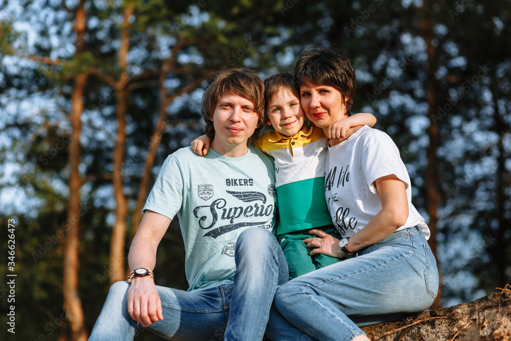 Fototapeta premium Father mother and son sit against the background of the forest