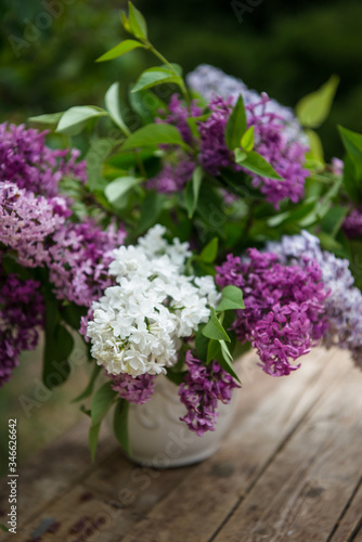 Lilac spring flowers in vase on wooden background. 