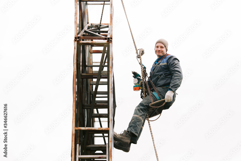 Industrial climber repair billboard. Risky job. Work on height. Metal construction. Electric screwdrive.