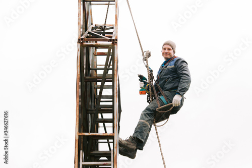 Obraz na płótnie Industrial climber repair billboard. Risky job. Work on height. Metal construction. Electric screwdrive. w salonie