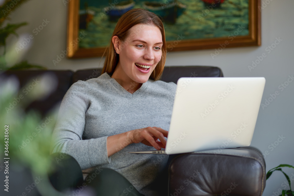 Happy young beautiful woman using a laptop computer at home