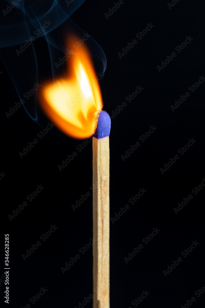 Single matchstick on fire in front of black background. Single matchstick on fire in front of black background.