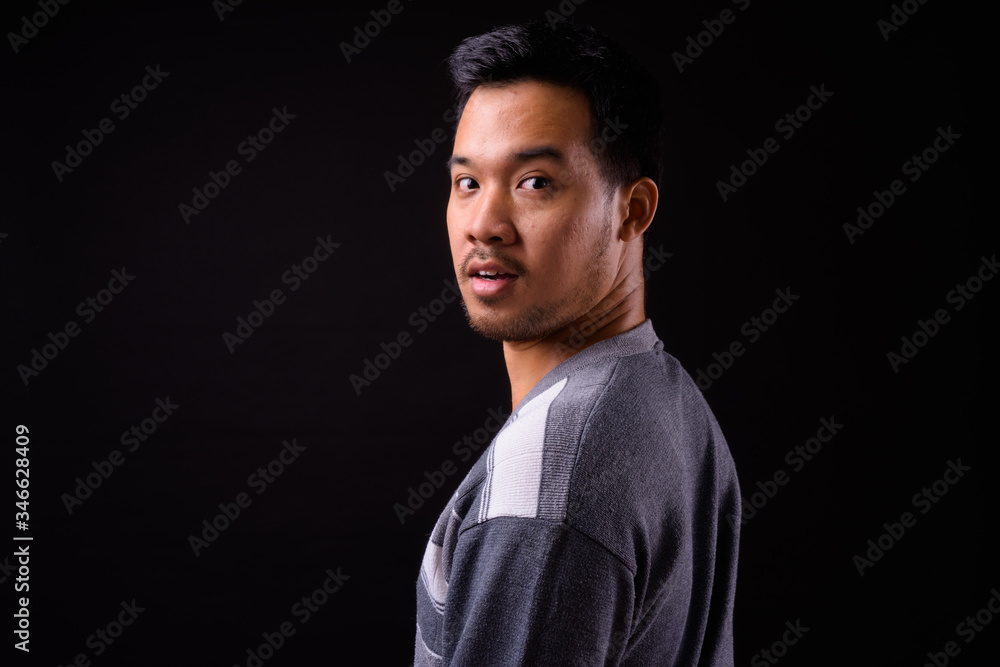 Rear view of young Asian man looking at camera Rear view of young Asian man looking at camera