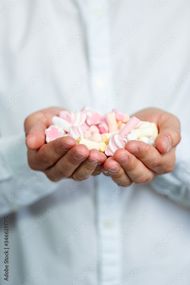 A man eats marshmallows from his hands. Bright man portrait. Sweets in the hands of a guy. Cheerful man portrait with sweets A man eats marshmallows from his hands. Bright man portrait. Sweets in the hands of a guy. Cheerful man portrait with sweets