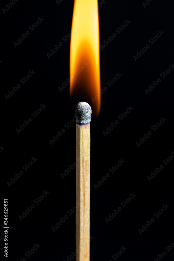 Single matchstick on fire in front of black background. Single matchstick on fire in front of black background.