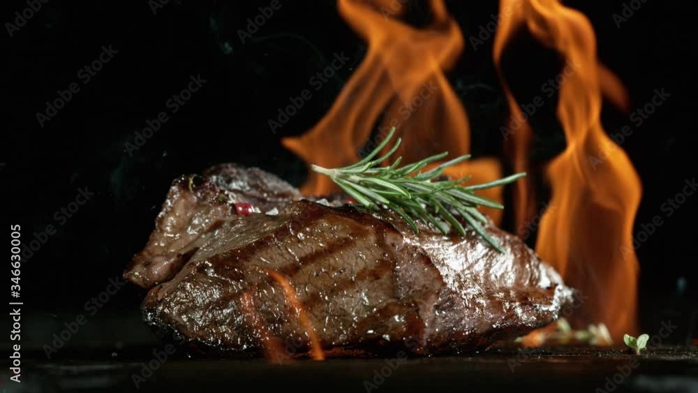 Close-up of falling tasty beef steak on iron cast grate, super slow motion, filmed on high speed cinematic camera at 1000 fps. Close-up of falling tasty beef steak on iron cast grate, super slow motion, filmed on high speed cinematic camera at 1000 fps.