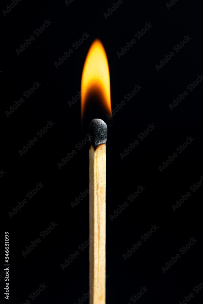 Single matchstick on fire in front of black background. Single matchstick on fire in front of black background.