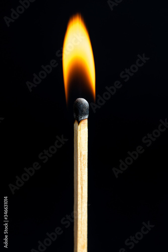 Single matchstick on fire in froSingle matchstick on fire in front of black background.nt of black background.