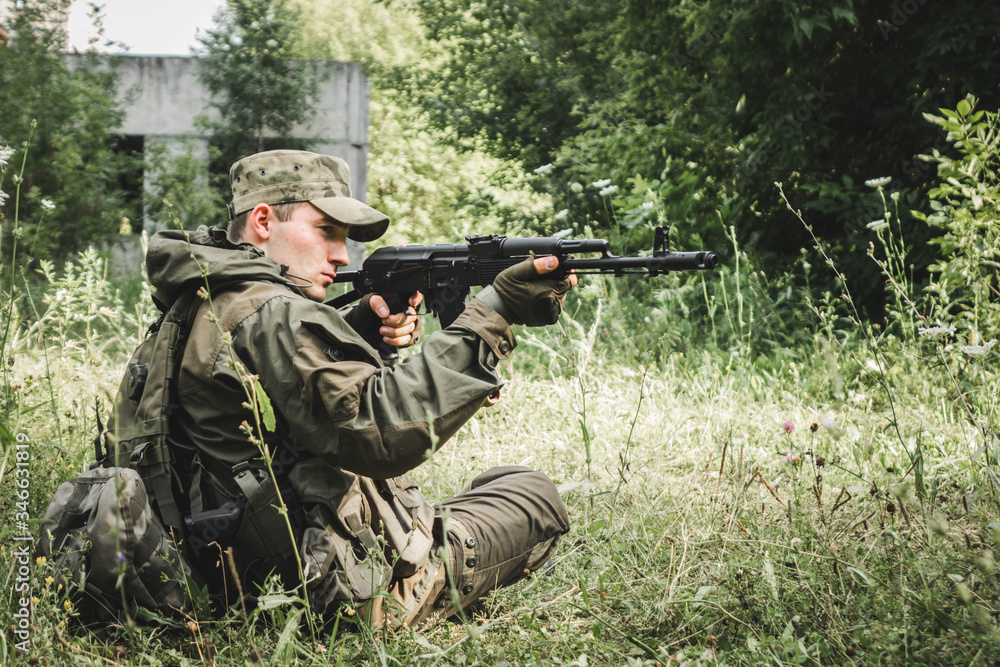 a soldier aims a rifle sitting in the bushes a soldier aims a rifle sitting in the bushes