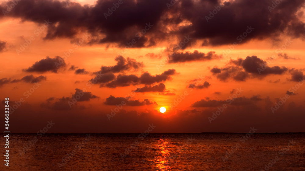 Beautiful sunset seascape with orange, purple and blue colored sky and reflection on the sea. Calming romantic atmosphere of tropical beach at the ocean shore. Family summer holiday travel concept.