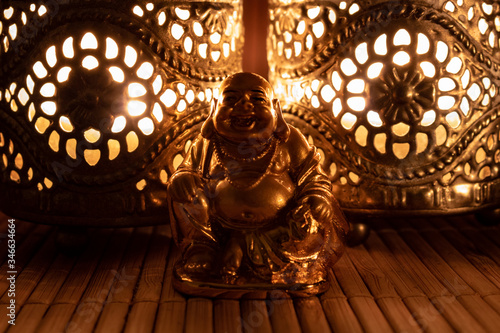 Golden budhha monk sculpture illuminated by oriental candle light, close up.  photo