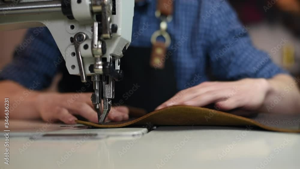 Closeup leather maker hands stitching a wallet in sewing machine. Working process of leather craftsman. Closeup leather maker hands stitching a wallet in sewing machine. Working process of leather craftsman.