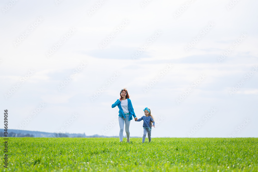 little girl child and mother woman run and jump, green grass in the field, sunny spring weather, smile and joy of the child, blue sky with clouds little girl child and mother woman run and jump, green grass in the field, sunny spring weather, smile and joy of the child, blue sky with clouds