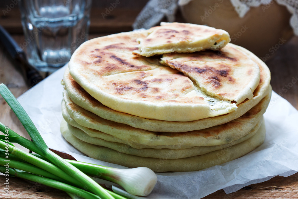 Traditional in different countries pies stuffed with cheese and herbs, fresh garlic and wine on a wooden background.